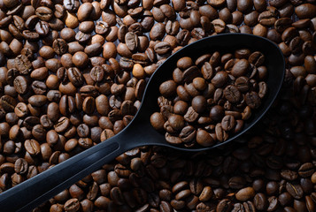 Coffee. Black spoon with coffee on old brown table studded with coffee