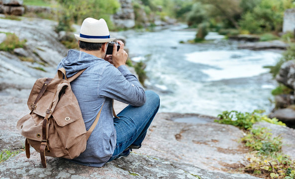 Man making pictures with a camera while traveling. Natural canyon with view of the mountain river. Concept of travel.