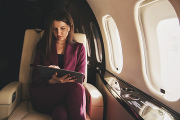 Obraz premium piękna młoda kobieta siedzi w samolocie i pracuje na laptopie
