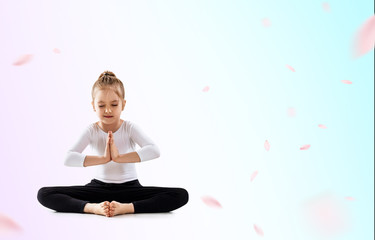 Cute little girl meditating in lotus position