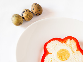 Slice of pepper stuffed with sheep cheese and quail eggs on white plate and white background. Quail eggs, space for text, cheese
