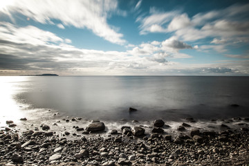 Standing at the shore where the ocean meets the land. It's the baltic sea in winter. A quiet, smooth evening in the middle of blue and grey light an colour.