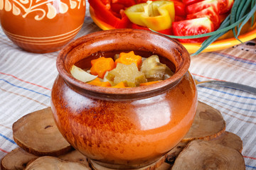 Traditional rustic home  gulyas, with raw vegetables and spices in clay pots on  wooden table.