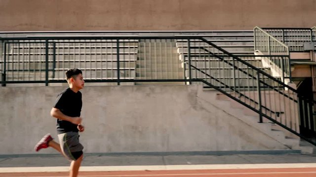 12 year old boy runs on his school's track.