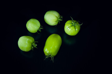 Green tomatoes on black wood