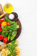 Fresh garden tomatoes, cucumbers and pasta on cooking table