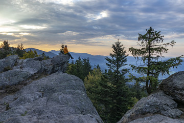 Man sits at the rock in the Bavarian forest and looks into the distance