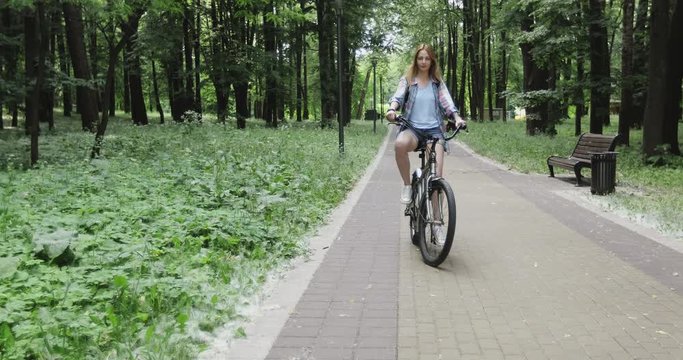 A young girl is riding bicycles in summer parks.