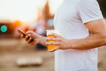 Close up of a man using mobile smart phone and holding beer
