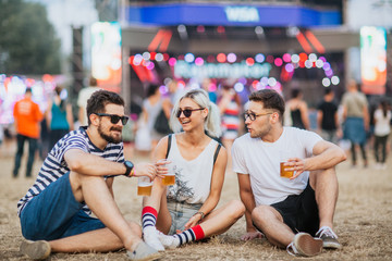 Friends drinking beer and having fun at music festival - obrazy, fototapety, plakaty