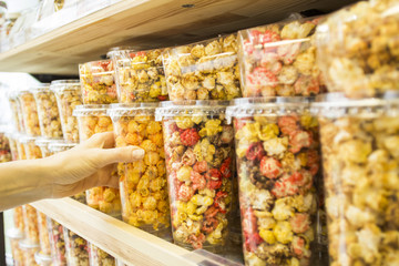 The hand holds popcorn with caramel, fruit and different flavors.