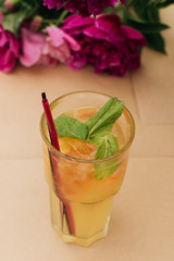 Delicious tropical cocktail with mint leaves, pink peony flowers on table