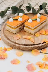 Two pieces of delicious cake on wooden board decorated with floral petals