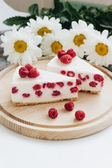 Two pieces of delicious cake with raspberries on wooden board