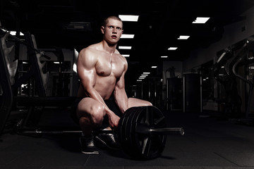 Fototapeta na wymiar Muscular strong athletic men pumping up muscles and training in gym. Handsome bodybuilder guy doing exercises with barbell.