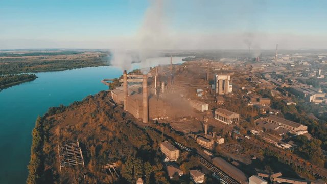 Aerial view of the Industrial Plant with Smoking Pipes near the City. Industrial zone. View from the drone to the Metallurgical factory near the river. Poor environmental conditions of the environment