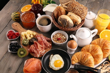 breakfast on table with bread buns, croissants, coffe and juice.