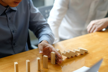 Businessman hand stopping the domino effect. executive and risk control concept.