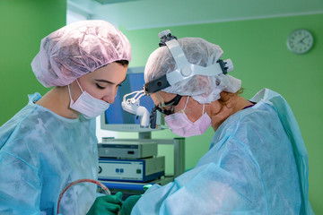 Surgeon and his assistant performing cosmetic surgery on nose in hospital operating room. Nose...