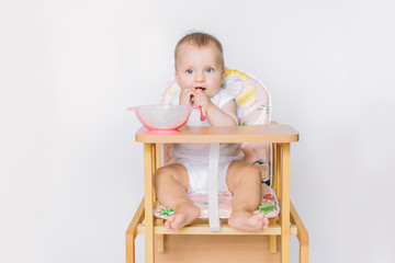 portrait of happy young baby girl sitting on high chair and feed her self