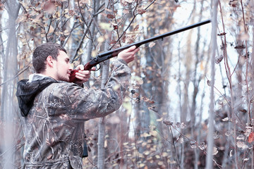 Naklejka premium A man in camouflage and with a hunting rifle in a forest on a sp