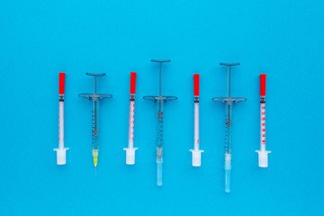 Syringes organized in a row over blue background, top view. Mock up health care medical background.
