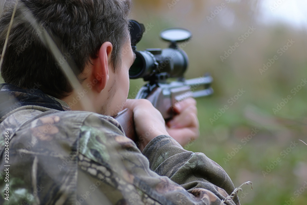 Wall mural man in camouflage and with guns in a forest belt on a spring hun