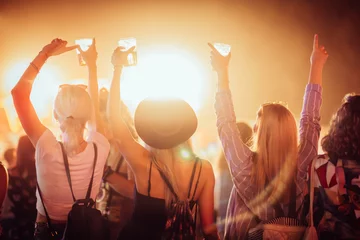 Foto op Plexiglas Back view of group of female friends at music festival drinking beer and dancing  © Astarot