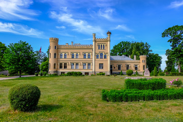 Fototapeta premium vintage yellow brick manor in countryside with flowers in front of it