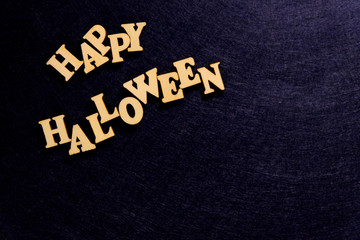 Stylish inscription HAPPY HALLOWEEN on a dark blue background. Words of wooden letters. Copy space.