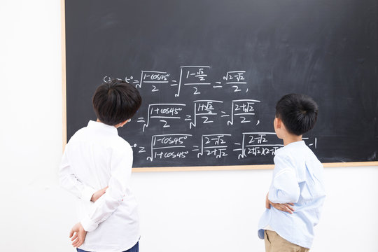 Primary school boy standing in front of the blackboard
