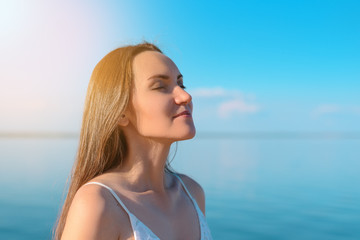 Close - up of a young brunette breathes clean sea air on the background of clear sky and sea, fresh...