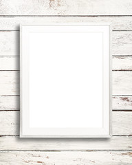 Blank white picture frame on white wood background.