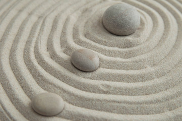 Pyramids of gray zen stones on the sand with wave drawings. Concept of harmony, balance and meditation, spa, massage, relax