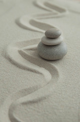 Fototapeta na wymiar Pyramids of gray zen stones on the sand with wave drawings. Concept of harmony, balance and meditation, spa, massage, relax