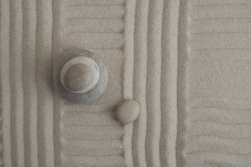 Pyramids of gray zen stones on the sand with wave drawings. Concept of harmony, balance and meditation, spa, massage, relax