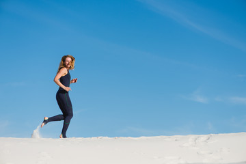 Fototapeta premium Woman running on sand in sport wear