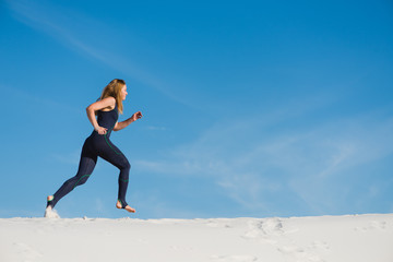 Active woman in sport wear jogging in desert