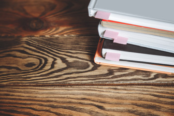 Stack of books with bookmarks on a wooden table. Copy space.