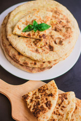 tortillas with potatoes, pita, chapati, decorated with a leaf of basil, on a black background, oriental food