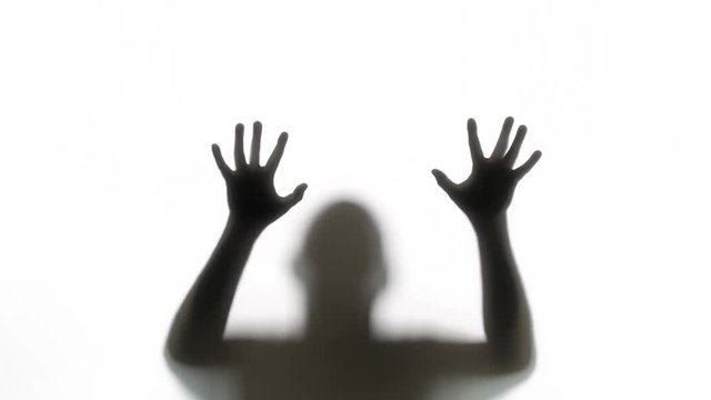 Silhouette of a zombie trying to get through a glass window. Great for Halloween.