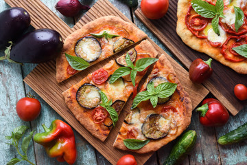 Healthy vegetarian food. Homemade Italian pizzas with aubergines, tomatoes and basil on oak cutting boards with raw ingredients