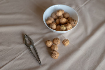 Nutcracker and walnuts in a bowl on a table covered with a tablecloth. Snack on the kitchen table.