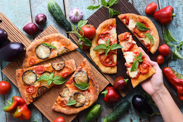 Woman hand and healthy vegetarian food. Homemade Italian pizzas with vegetables on oak cutting boards with raw ingredients
