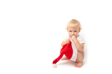 baby girl sitting on his haunches with a Santa Claus hat isolated on white background. child and christmas cap