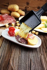 Foto auf Glas Delicious traditional Swiss melted raclette cheese on diced boiled or baked potato. © beats_