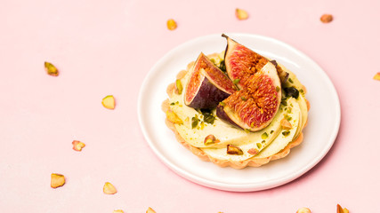 Delicious tart with fresh figs and pistachios on pink pastel backgrounds