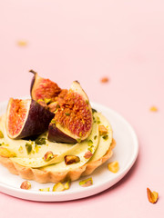 Delicious tart with fresh figs and pistachios on pink pastel backgrounds