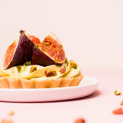 Delicious tart with fresh figs and pistachios on pink pastel backgrounds