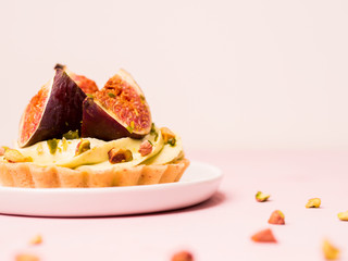 Delicious tart with fresh figs and pistachios on pink pastel backgrounds